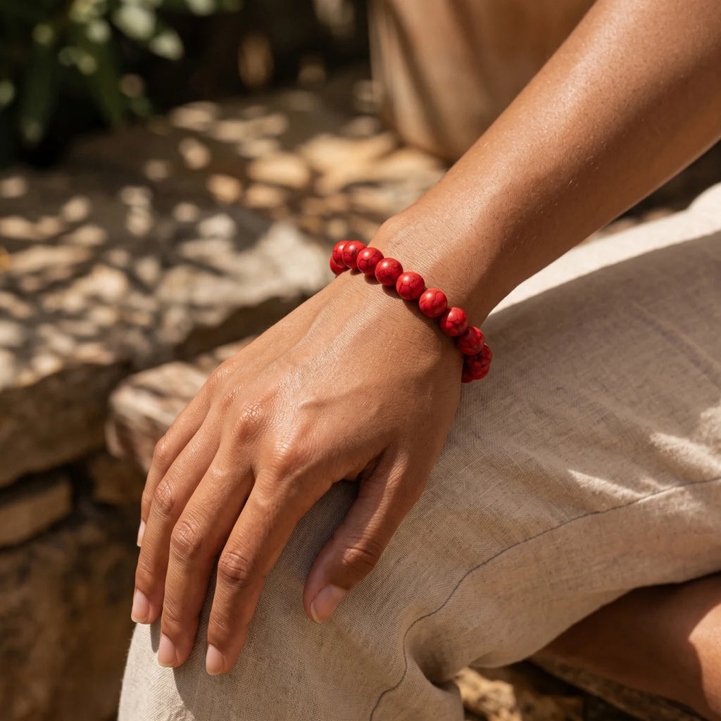 Pulsera elástica de howlita roja con bolitas de piedra en muñeca con pantalón de lino